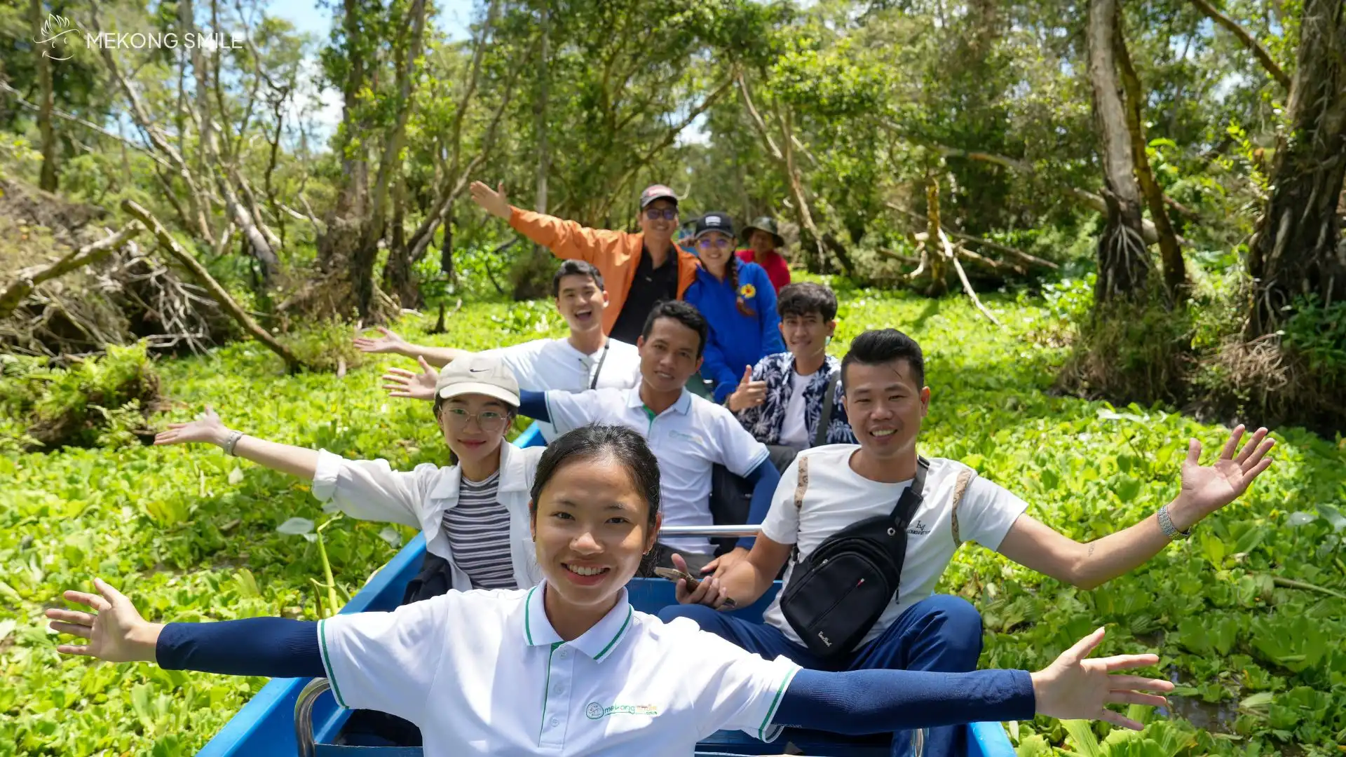 Travelers on a traditional sampan, gracefully moving through the serene Tra Su forest