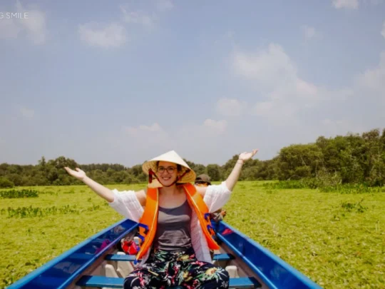 A tourist wearing a life vest for safety while riding a sampan, highlighting the tour's safety measures