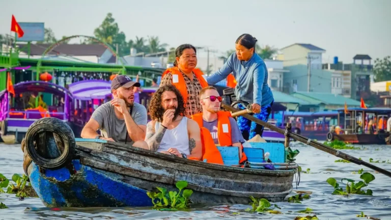 Travelers beside a vendor boat at Cai Rang Floating Market in Can Tho