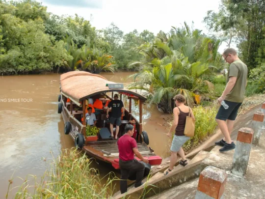 Guests boarding a traditional wooden boat for the Me Kong Smile tour in Vinh Long, Vietnam
