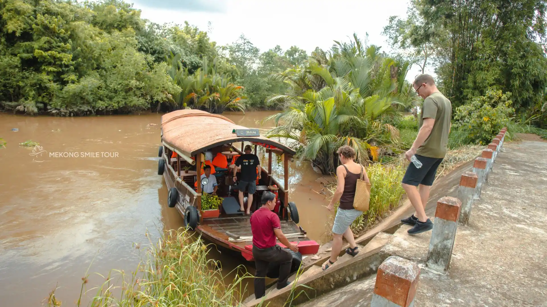 Guests boarding a traditional wooden boat for the Me Kong Smile tour in Vinh Long, Vietnam