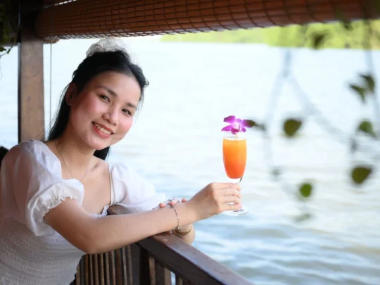 Woman holding a fruit drink by the river – Mekong Smile Can Tho Sunset Tour
