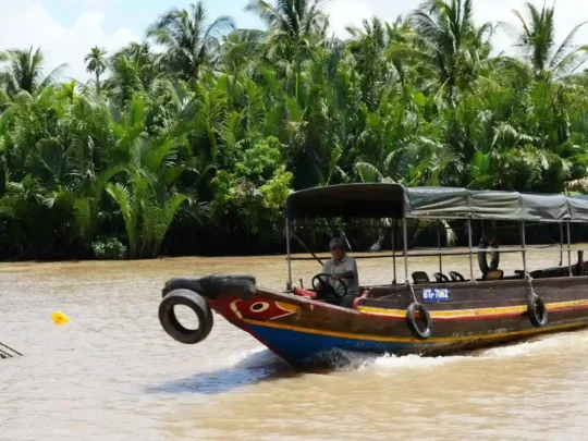 Wooden passenger boat traveling along a river in Ben Tre