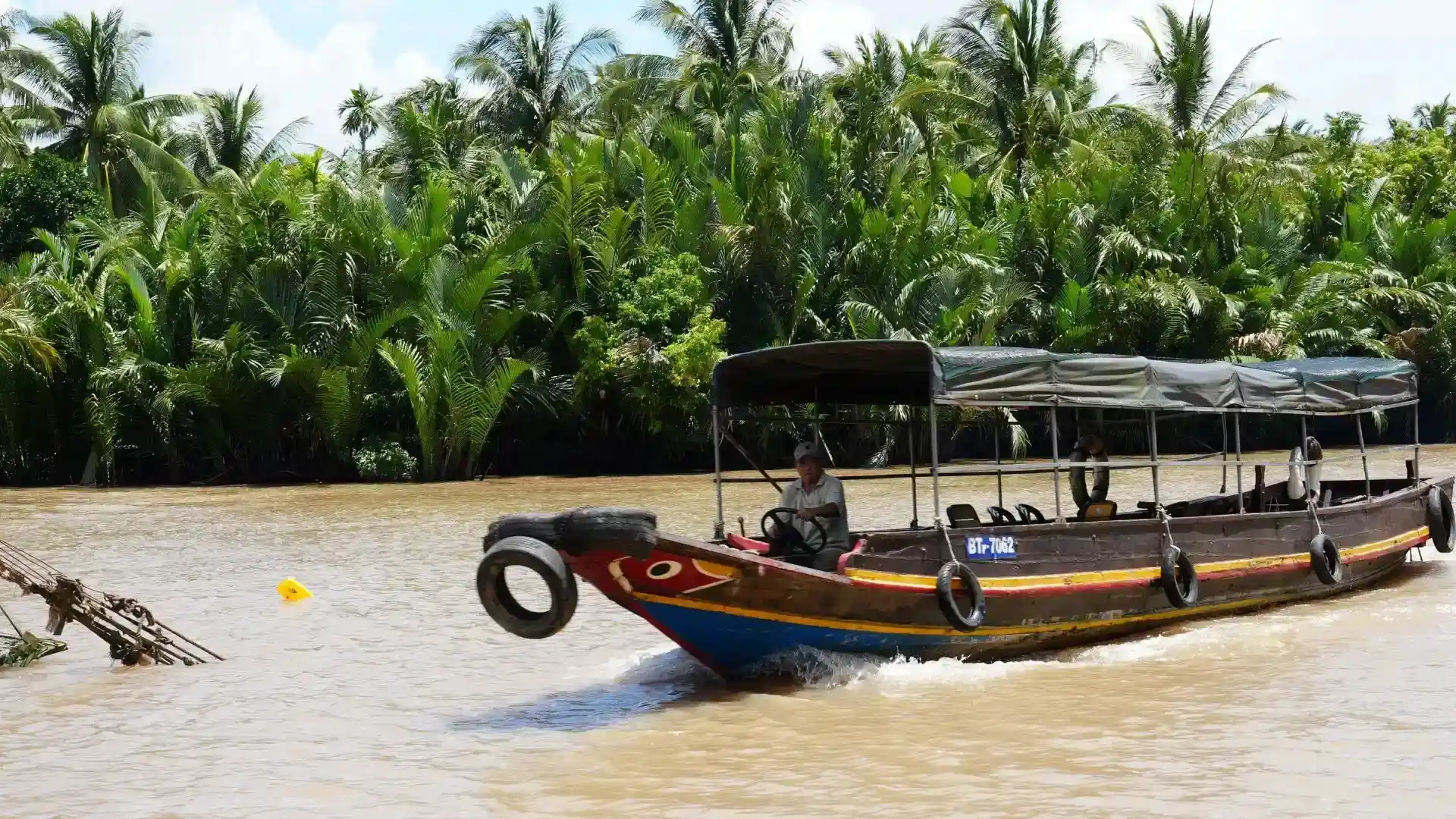 Wooden passenger boat traveling along a river in Ben Tre