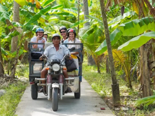Guests riding a Xe Loi along a village road in Ben Tre