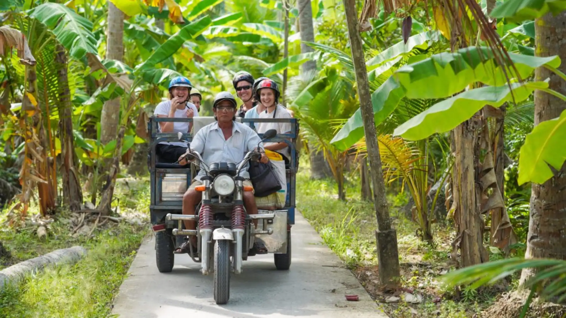 Guests riding a Xe Loi along a village road in Ben Tre